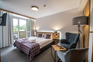 a bedroom with a bed and a chair and a window at Nowa - Ski SPA Hotel in Karpacz +107 photos