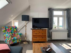 sala de estar con TV y silla en Vierseitenhof Hasenfelde - Ferienwohnung Feldblick, en Steinhöfel