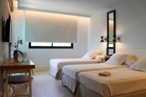 a hotel room with two beds and a table at Hotel Almirante in Alicante