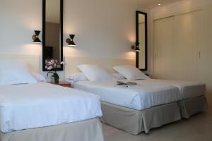 two beds in a bedroom with white sheets at Hotel Almirante in Alicante