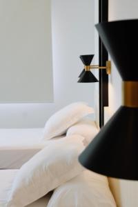 a bed with white pillows and a black lamp at Hotel Almirante in Alicante