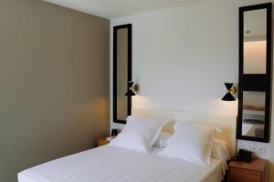 a bedroom with a white bed with two mirrors at Hotel Almirante in Alicante