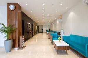 a lobby with blue couches and tables and a clock at Hotel Regal Grand in Bhopal