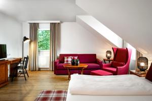 ein Wohnzimmer mit einem roten Sofa und einem Tisch in der Unterkunft Hotel Prinzregent München Messe in München
