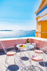 un tavolo e sedie su un balcone con vista sull'oceano di Villa Selena a Ermoupoli
