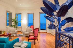 a living room with blue chairs and a large plant at Villa Selena - 1830s Art-House Suites in Vaporia, 50m from Asteria Beach in Ermoupoli