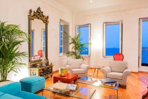 a living room with a mirror and blue chairs at Villa Selena - 1830s Art-House Suites in Vaporia, 50m from Asteria Beach in Ermoupoli