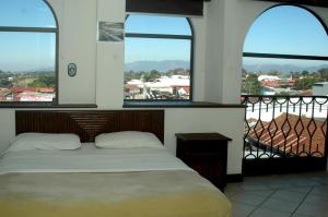 a hotel room with two beds and a window at Alajuela Backpackers Airport Hostel in Alajuela