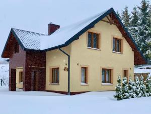 una casa con nieve en el techo en la nieve en Alpina en Krynica Zdrój