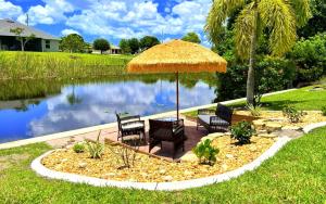 ein Tisch und Stühle unter einem Sonnenschirm neben einem Teich in der Unterkunft !NEW! Villa Waterview in Cape Coral