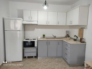 a kitchen with white cabinets and a white refrigerator at Moschoula Villa - Apartment 1 in Limenas