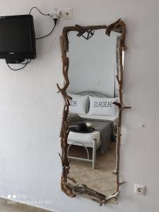 een spiegel met een houten frame, een bed en een tv bij Moschoula Villa - Apartment 1 in Limenas