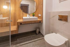 a bathroom with a toilet and a sink and a mirror at VacationClub – Jantaris Apartament A 35 in Mielno