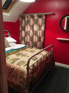 ein Schlafzimmer mit einem Bett mit einer roten Wand in der Unterkunft Charming 3-Bed House in Abergele Wales UK in Abergele