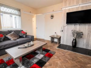 a living room with a couch and a flat screen tv at 55 Marine Road in Abergele