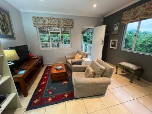 a living room with two couches and a tv at PIGEONWOOD Forest Cottage in Ballito