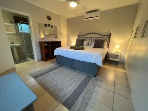 a bedroom with a large bed and a bathroom at PIGEONWOOD Forest Cottage in Ballito