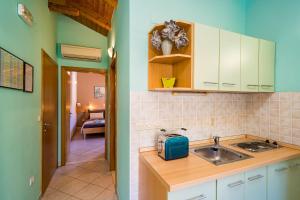 a kitchen with white cabinets and a sink and a hallway at Apartments Vodnica in Zaton