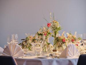 une table avec un tissu de table blanc et des fleurs dans l'établissement Dorint Parkhotel Frankfurt / Bad Vilbel, à Bad Vilbel