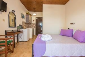 a bedroom with a bed with purple pillows and a kitchen at Notos Studios in Laganas