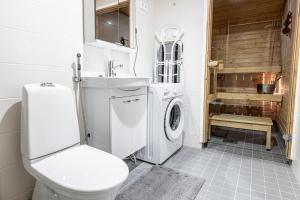 a bathroom with a toilet and a washing machine at SleepWell Apartment Rio with private sauna and parking in Helsinki