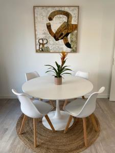 una mesa de comedor blanca con sillas blancas y una planta en Victorina by Basque Homes en San Sebastián