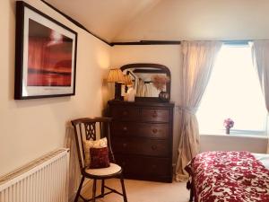 a bedroom with a dresser and a mirror and a chair at The Blue Cow in Fenstanton