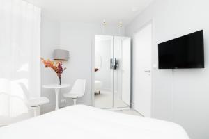 a white bedroom with a tv and a table and chairs at The Luxe Lake - Duke Housing in Créteil