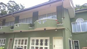 a green and white building with a balcony at AMARASINGHE GUEST HOUSE in Haputale
