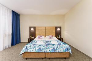 a bedroom with a large bed with blue curtains at Apartamenty Prywatne w Hotelu przy plaży DIVA Kołobrzeg in Kołobrzeg