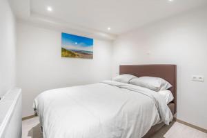a white bedroom with a bed with white sheets at Comfortabele, moderne studio zeedijk De Panne in De Panne