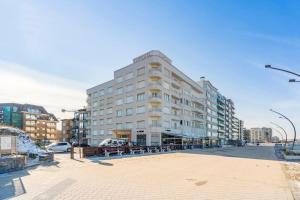 a large white building on a city street at Comfortabele, moderne studio zeedijk De Panne in De Panne