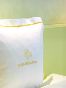 een witte tas met een logo op een bed bij Hotel Goldener Karpfen OHG in Fulda