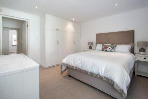 a white bedroom with a large bed and a bathroom at Birdsong in Hermanus