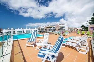 a group of lawn chairs sitting on a patio next to a pool at Fuseta Apartments - Bela Vista & Vista Mar - Penthouses in Fuzeta