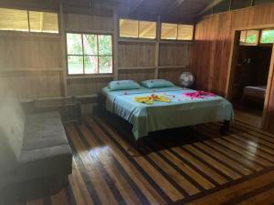 a bedroom with a bed and a couch and windows at Sabalo Lodge Tours and Cabins in Sierpe