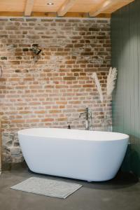 bañera blanca en una habitación con pared de ladrillo en La cabane du potager - Ferme de Linciaux en Ciney