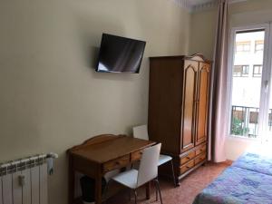 1 dormitorio con escritorio, vestidor y cama en Hostal Retiro, en Madrid