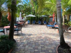 un patio con mesas, sillas y palmeras en Atlantic Shores Vacation Villas, en Palm Beach Shores