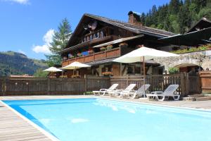 a swimming pool with chairs and a house at Les Chalets de la Serraz in La Clusaz