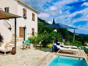 un patio con piscina y sombrilla en Villa Poggio, en Santa-Maria-Poggio