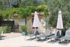 - un groupe de chaises longues et de parasols à côté de la piscine dans l'établissement Le bonheur au soleil, à Saint-Maximin-la-Sainte-Baume