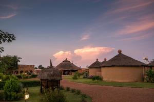 a group of huts with thatched roofs in a yard at Le Grand Calao in Ouagadougou