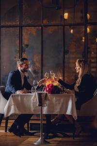 a man and woman sitting at a table with wine glasses at Mamaison Le Regina Boutique Hotel in Warsaw