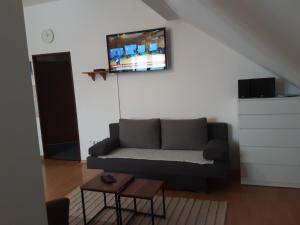 a living room with a couch and a tv on the wall at Račínská hospůdka in Velká Losenice