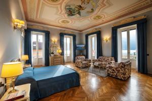 a bedroom with a bed and chairs and a ceiling at Hotel Villa Marie in Tremezzo