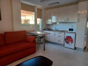 a living room with a red couch and a kitchen at Apartamentos Playa de Portio in Liencres