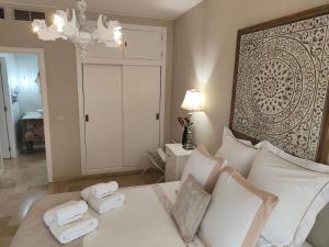 a bedroom with a white bed with towels on it at Apartamento La Judería de San Clemente in Seville