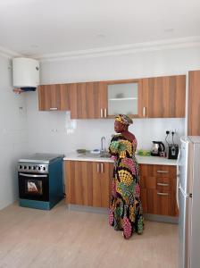 a woman is standing in a kitchen at The White House No.1 in Brufut