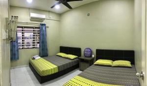 two beds in a room with yellow and gray at Kinaz homestay in Ipoh